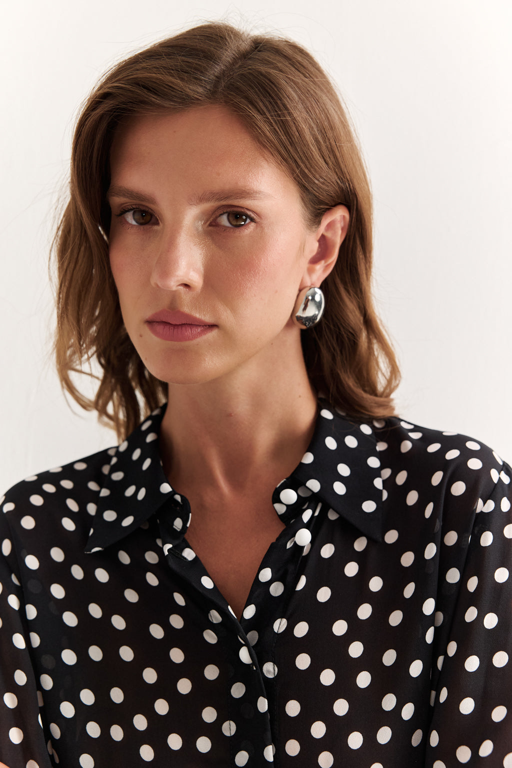Woman wearing a black polka dot blouse against a white background