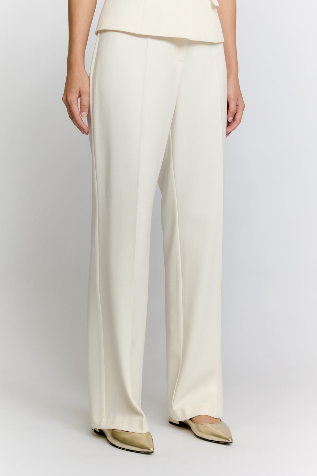 Person wearing white pants on a plain background