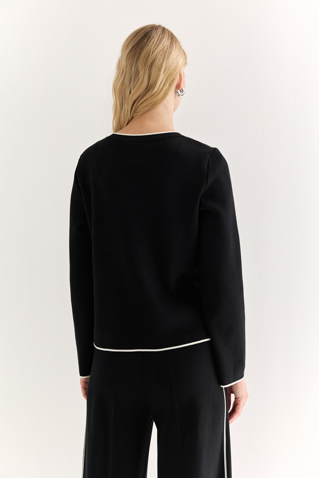 Person wearing a black outfit with white trim on a white background