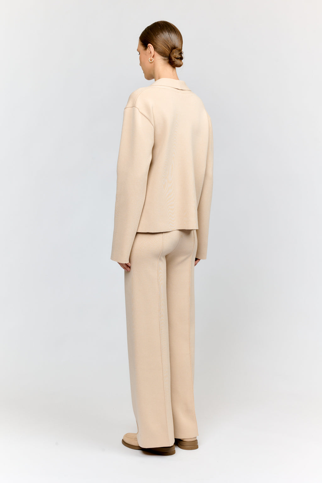 Person wearing a beige suit standing against a white background