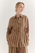 Woman wearing a brown striped shirt and pants on a white background