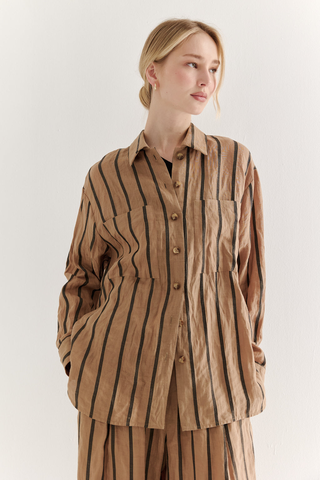 Woman wearing a brown striped shirt and pants on a white background