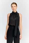 Woman wearing a black sleeveless top with a tie detail on a white background