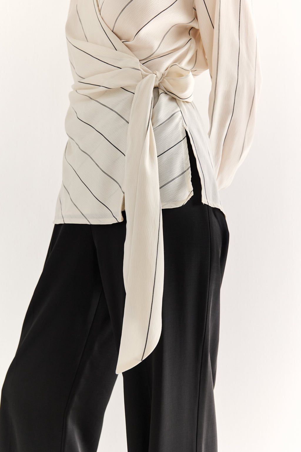 Person wearing a beige and black patterned top with a scarf, on a white background