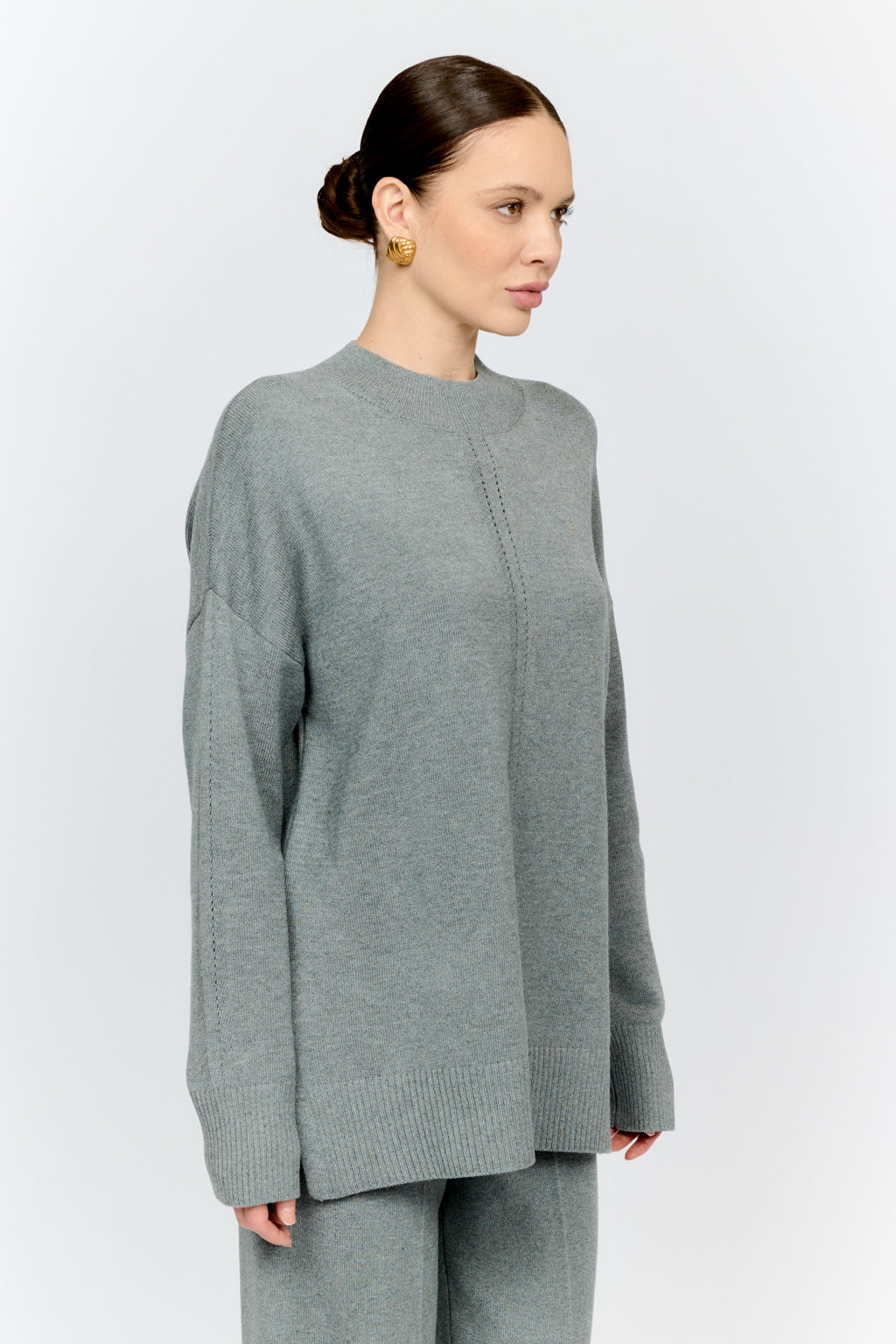 Woman wearing a gray sweater and pants on a white background