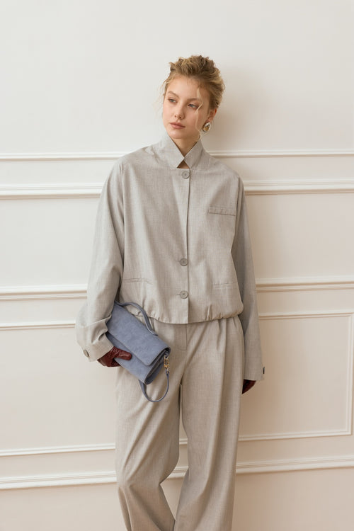 Woman in a beige outfit standing against a white wall