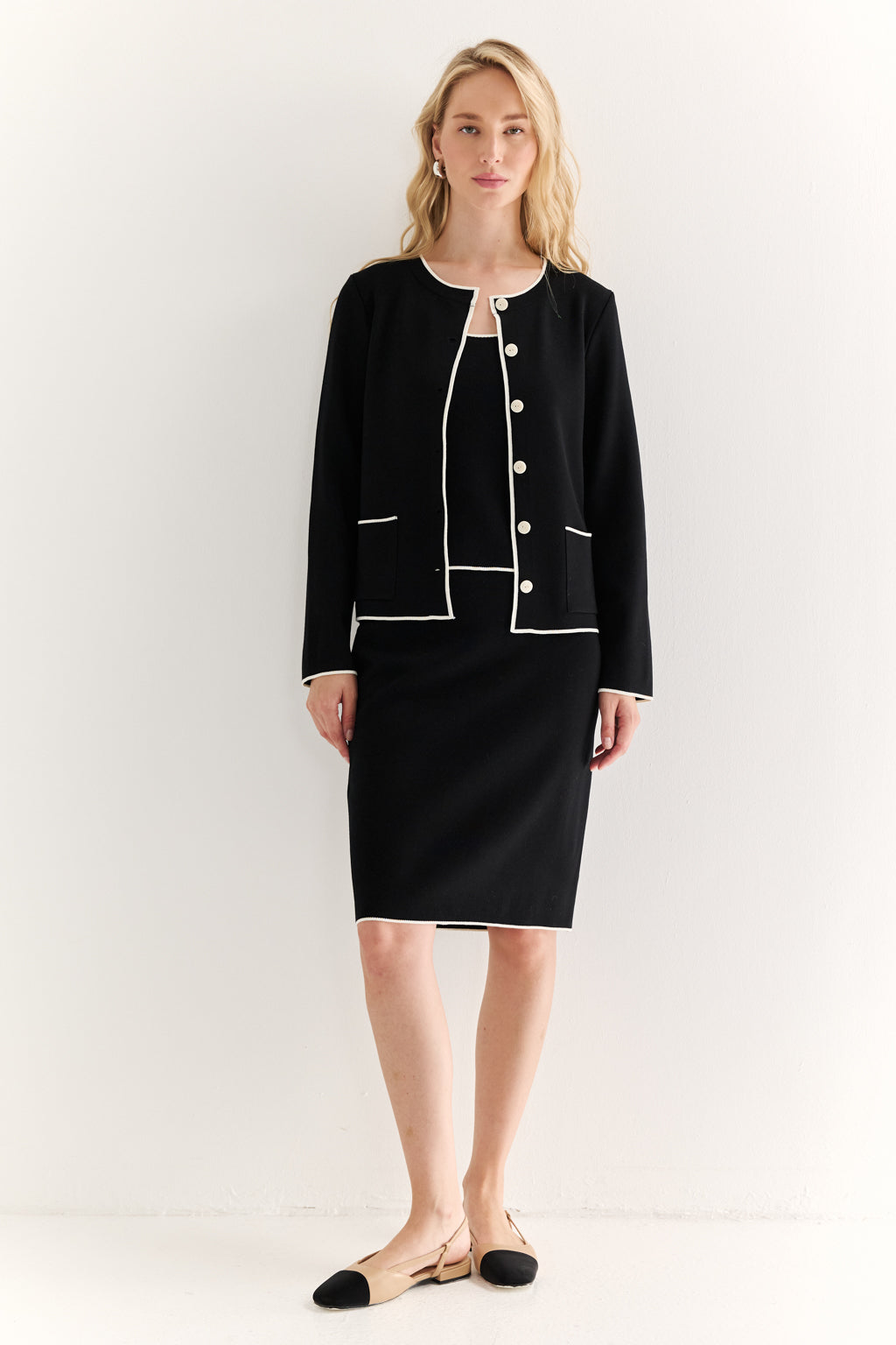 Woman wearing a black suit with white trim on a white background