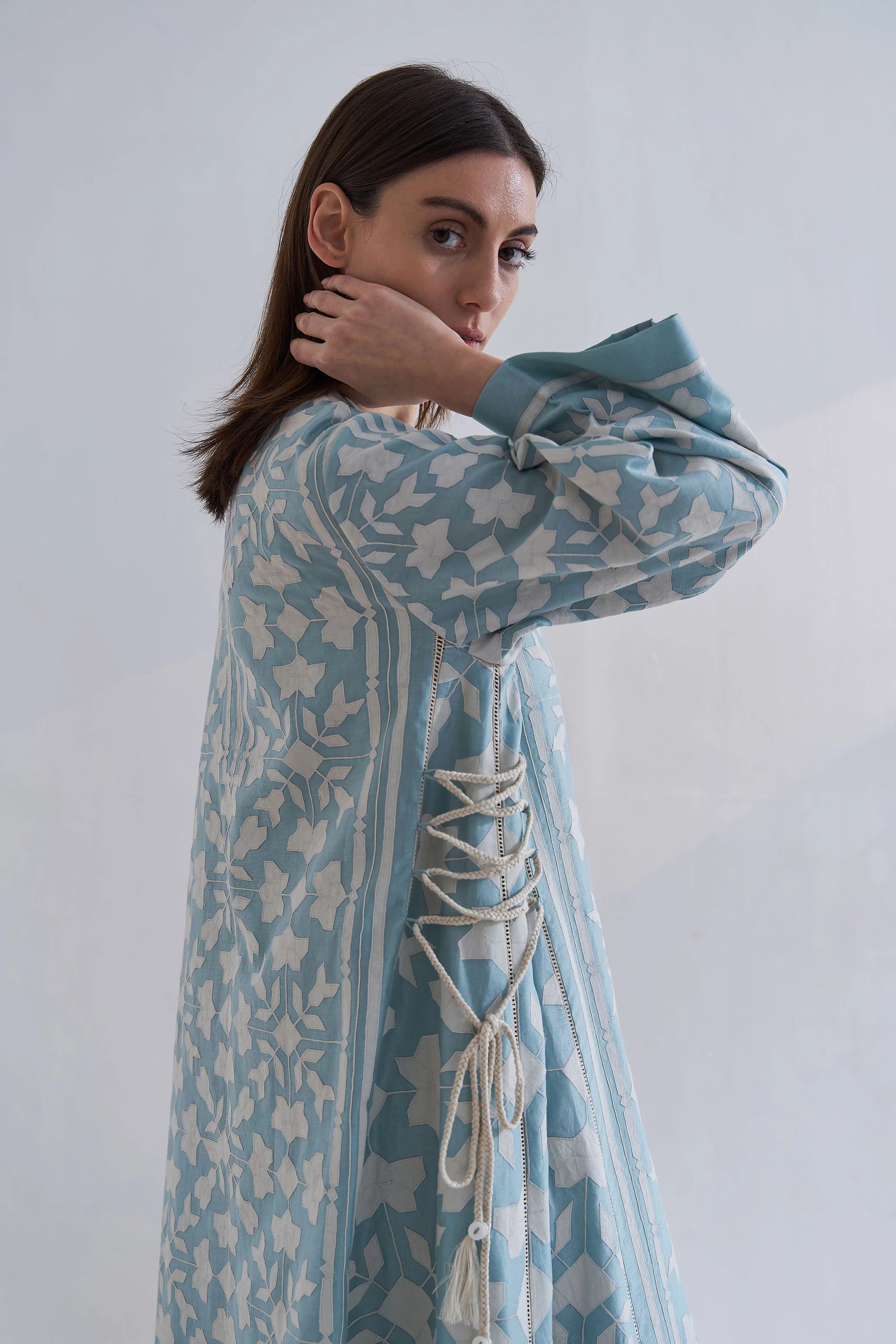 A floor-length cerulean blue Chanderi dress featuring ivory geometric hand-cut appliqué along the hemline and sleeves.