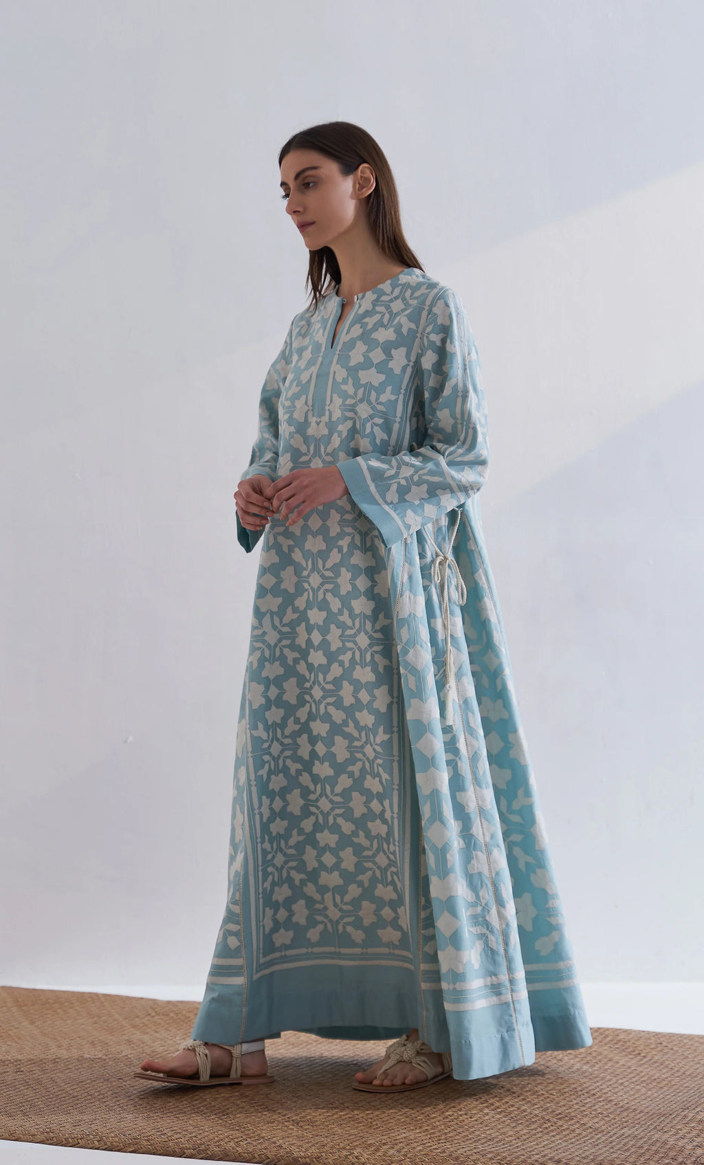 A floor-length cerulean blue Chanderi dress featuring ivory geometric hand-cut appliqué along the hemline and sleeves.