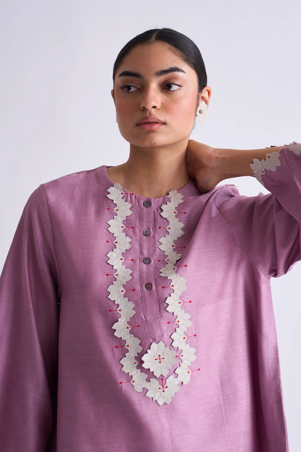 A model in a blush pink A-line Chanderi shirt with ivory geometric hand-cut appliqué along the hem and sleeves, paired with matching ivory pants.