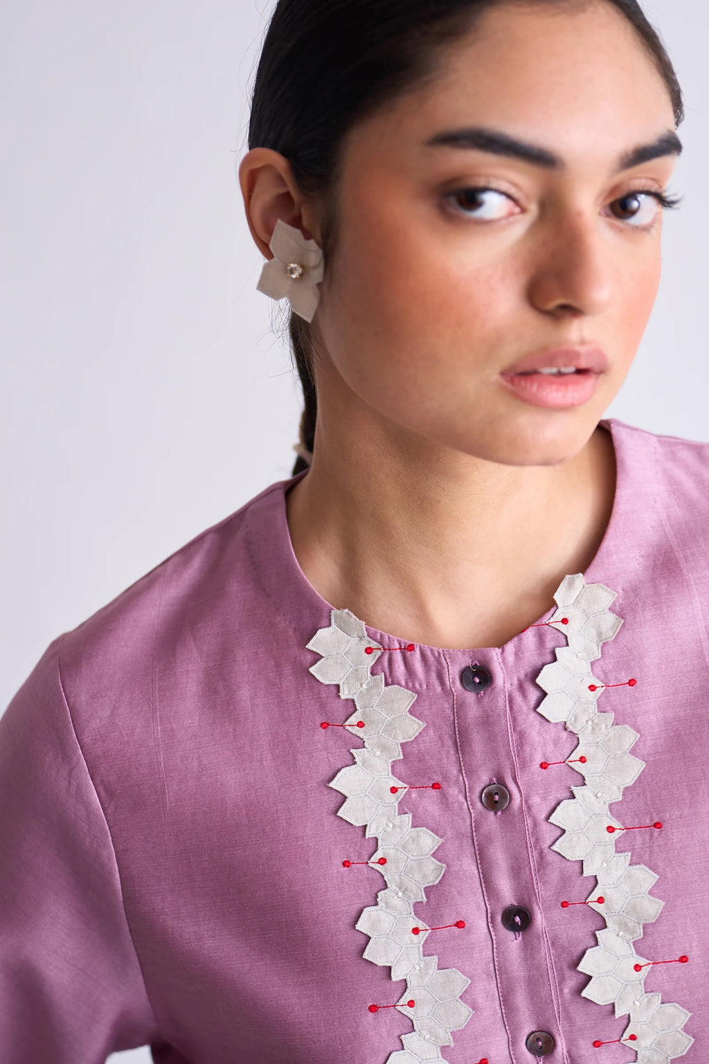 A model in a blush pink A-line Chanderi shirt with ivory geometric hand-cut appliqué along the hem and sleeves, paired with matching ivory pants.
