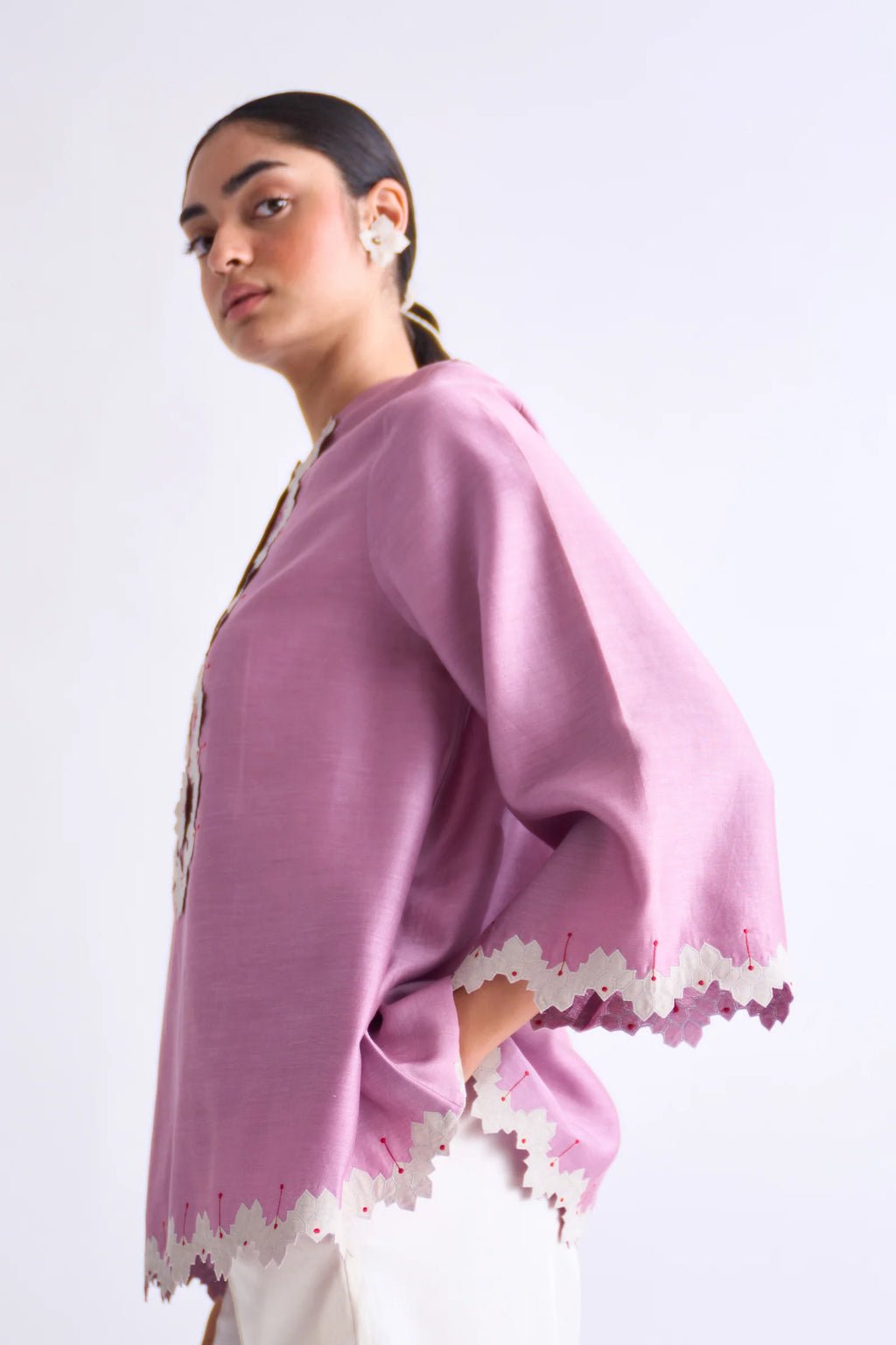 A model in a blush pink A-line Chanderi shirt with ivory geometric hand-cut appliqué along the hem and sleeves, paired with matching ivory pants.