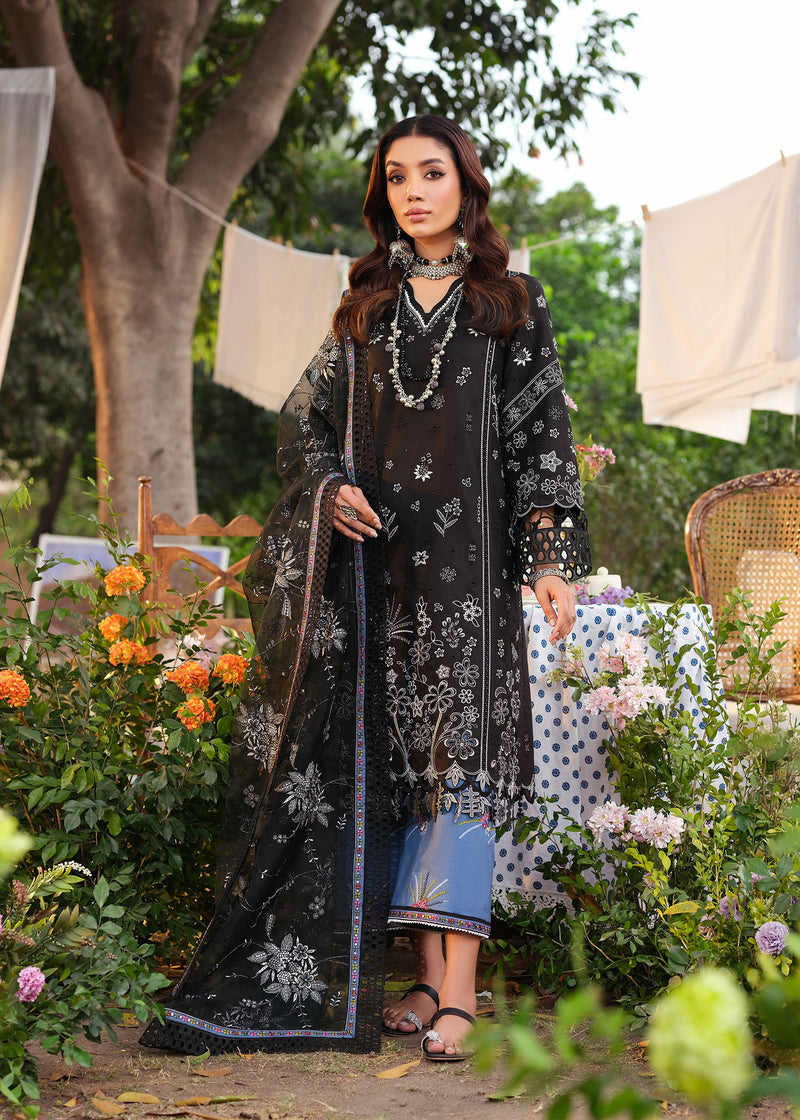 Woman in a black floral dress standing in a garden with flowers and tables in the background