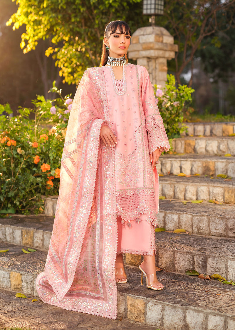 Woman in a pink traditional outfit standing on stone steps with greenery in the background