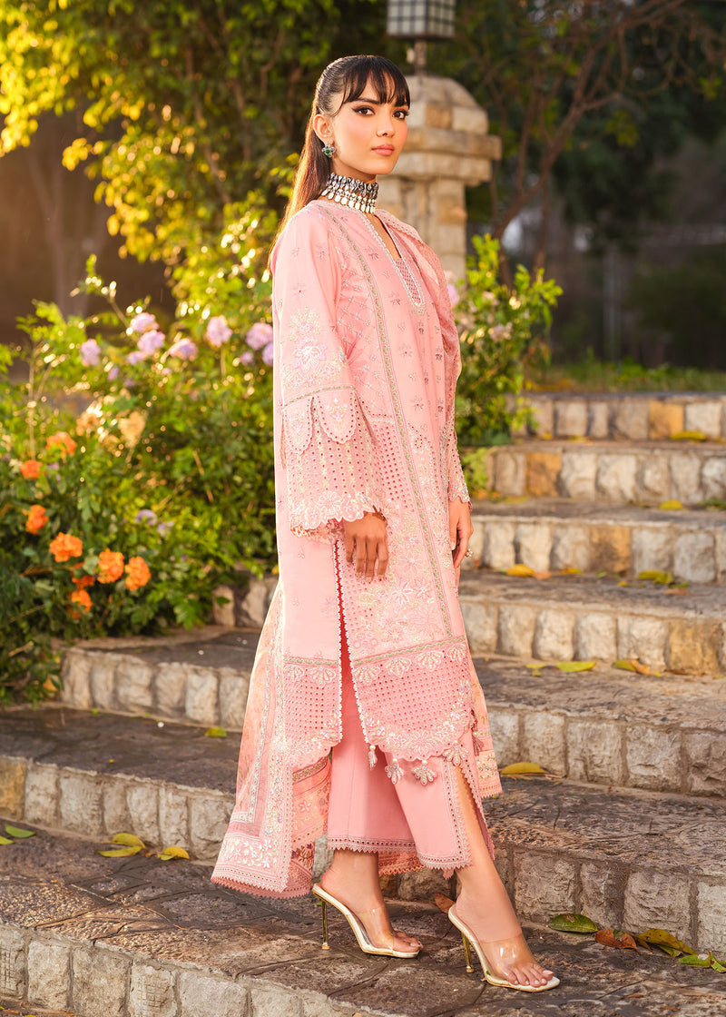 Woman in a pink traditional outfit standing on stone steps with greenery in the background