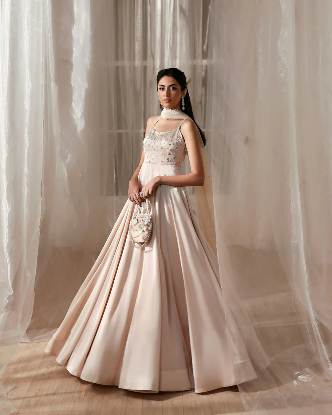 Woman in a elegant beige gown standing against a soft, neutral background