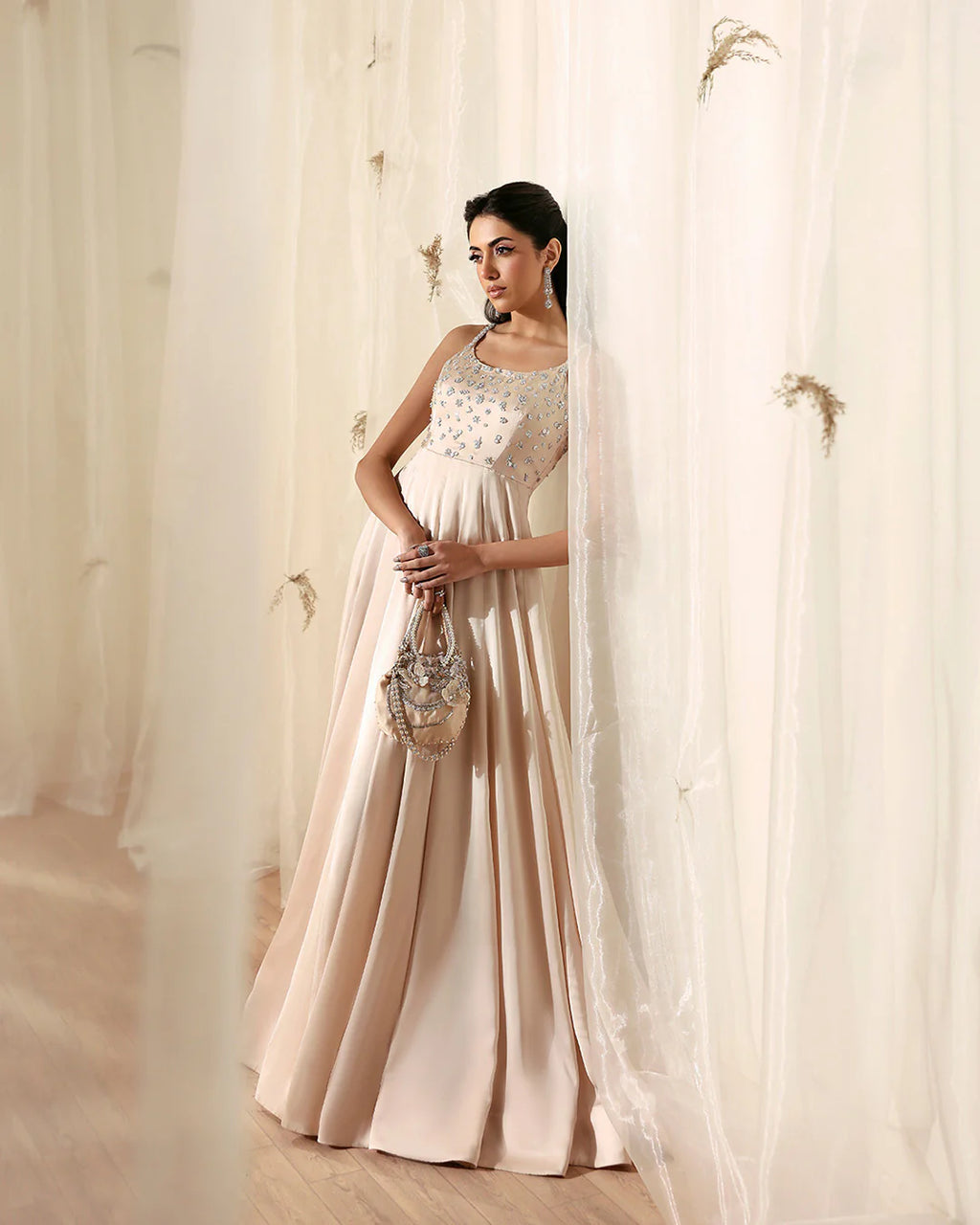 Woman in a light-colored dress standing behind sheer curtains
