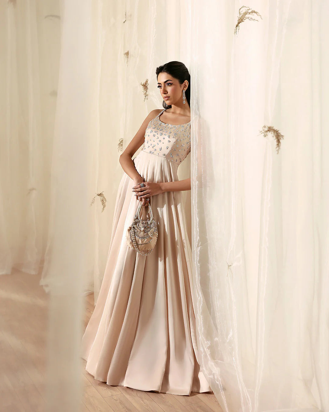Woman in a light-colored dress standing behind sheer curtains