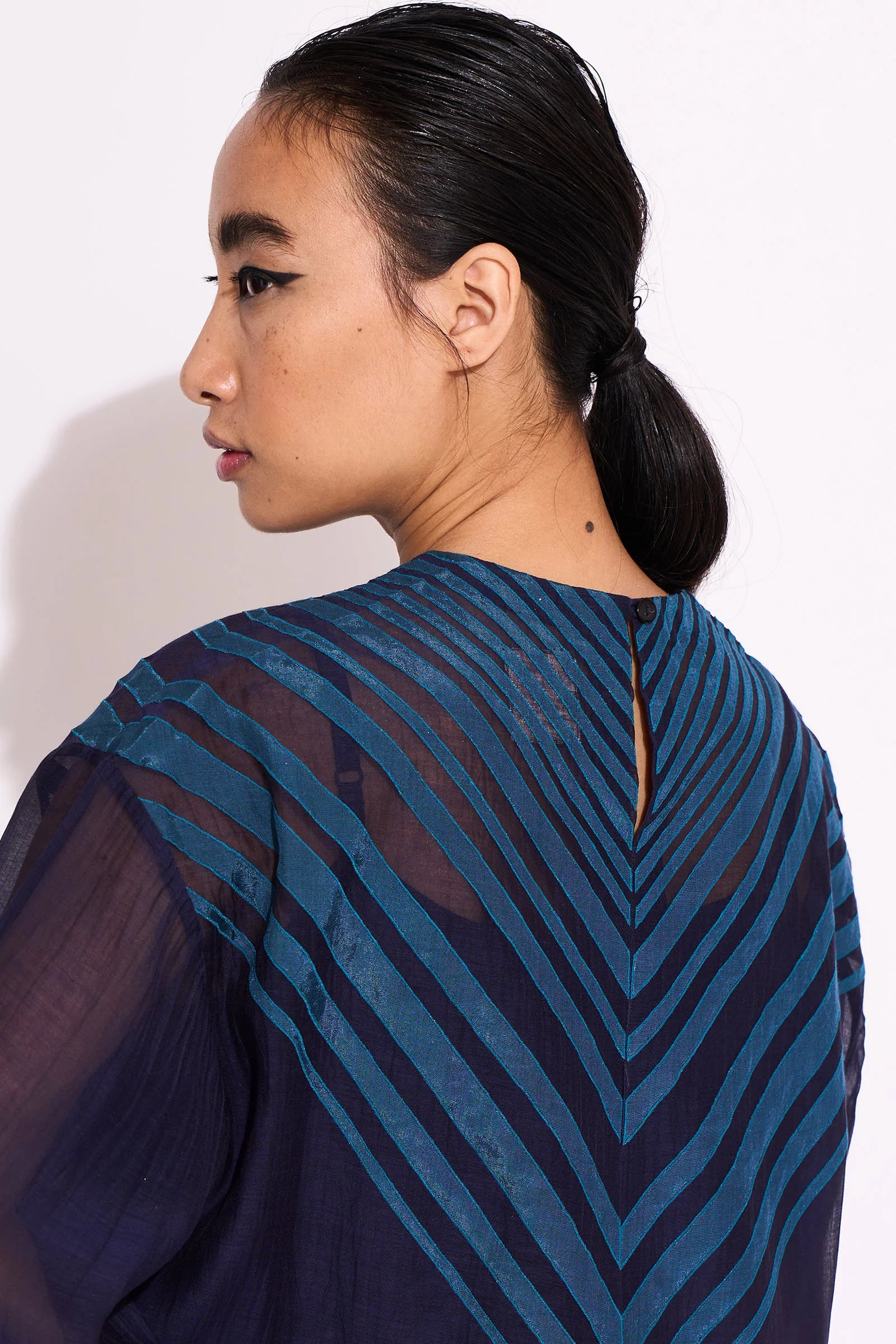 A navy blue Cotton Silk Chanderi shirt with teal geometric hand-cut appliqué on the front chest and back, featuring a pleated back design and scalloped edges.