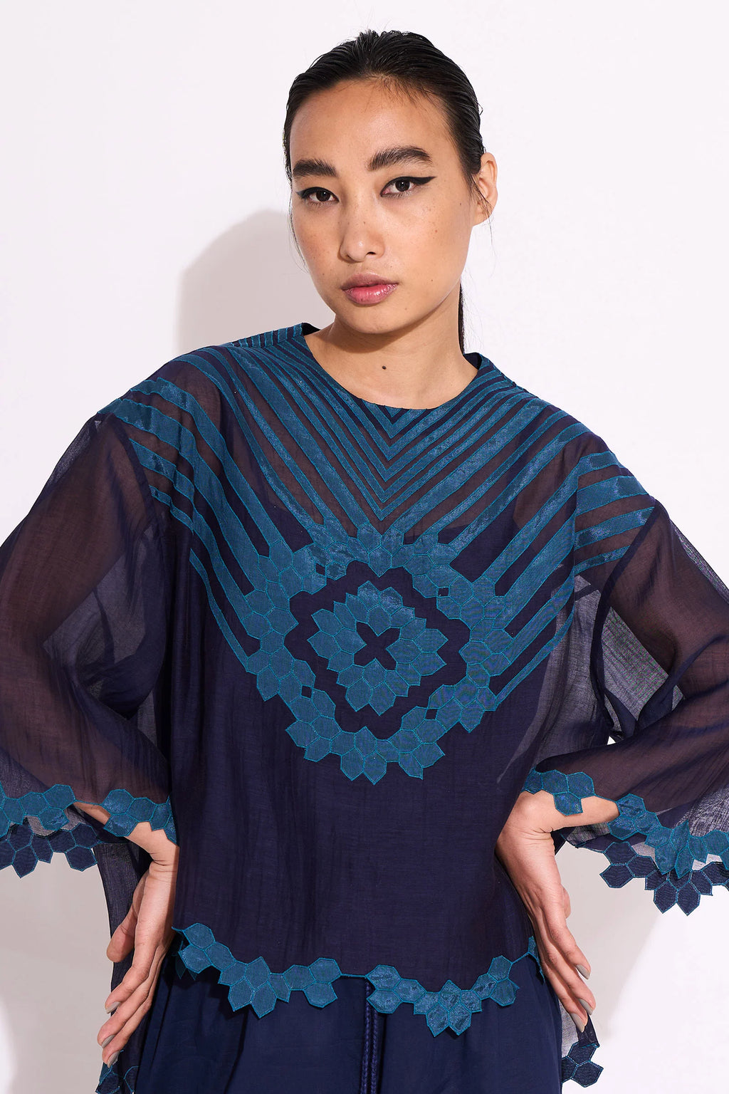 Woman wearing a dark blue dress with intricate lace details on a white background