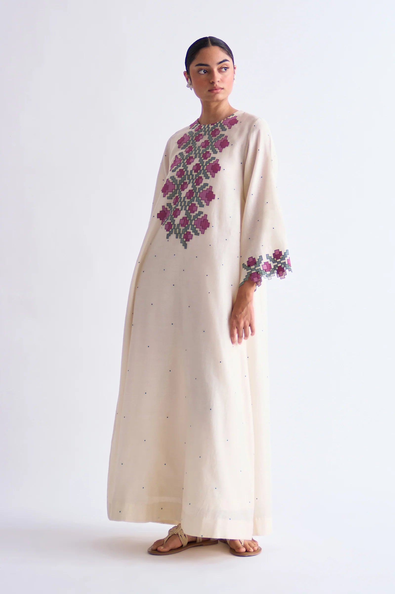An ivory floor-length Cotton Silk Chanderi circular dress with soft pink geometric hand-cut appliqué panels on the bodice and sleeves.