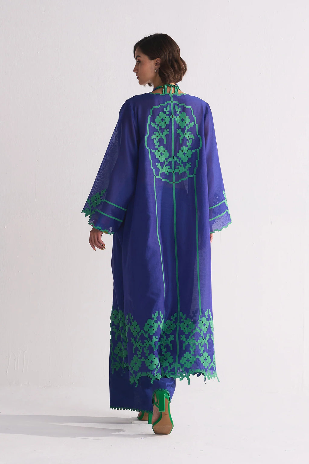 A long indigo Cotton Silk Chanderi jacket featuring a large green geometric floral appliqué on the back and matching cutwork along the hem and sleeves.