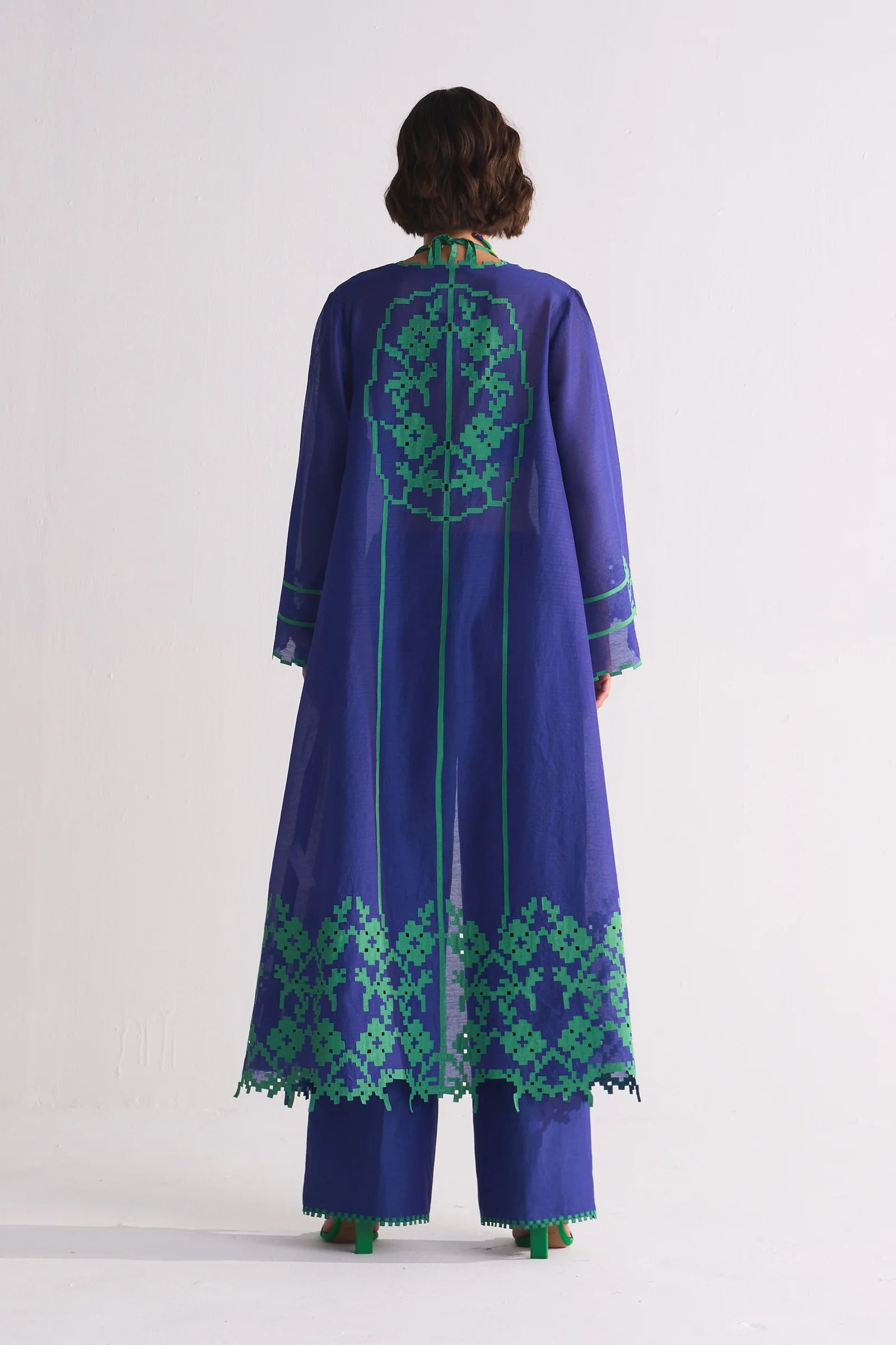 A long indigo Cotton Silk Chanderi jacket featuring a large green geometric floral appliqué on the back and matching cutwork along the hem and sleeves.