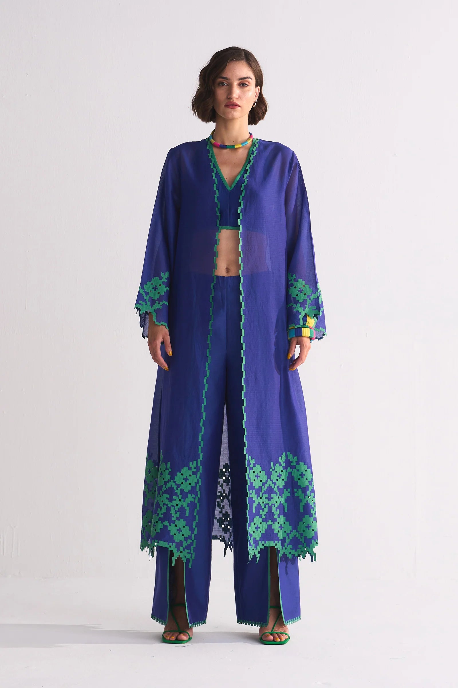 A long indigo Cotton Silk Chanderi jacket featuring a large green geometric floral appliqué on the back and matching cutwork along the hem and sleeves.