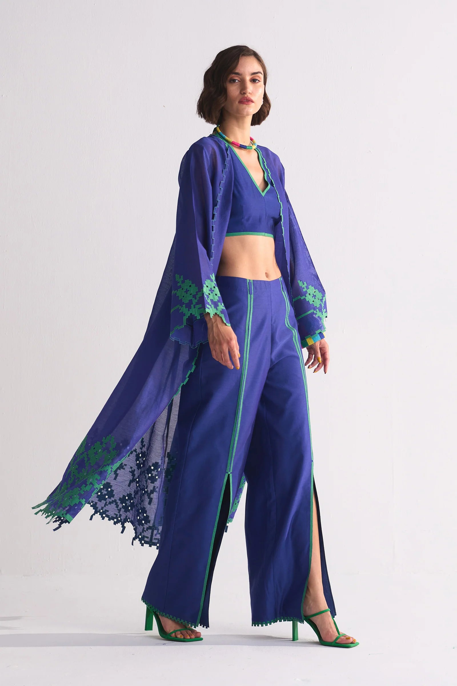 A long indigo Cotton Silk Chanderi jacket featuring a large green geometric floral appliqué on the back and matching cutwork along the hem and sleeves.