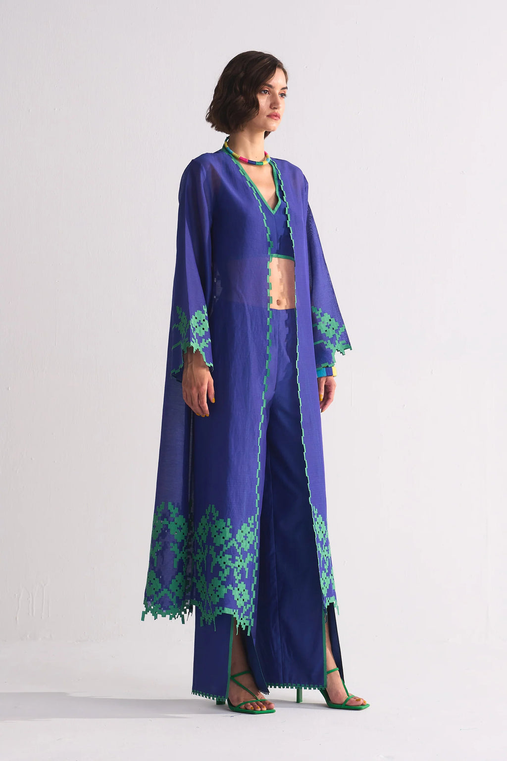 A long indigo Cotton Silk Chanderi jacket featuring a large green geometric floral appliqué on the back and matching cutwork along the hem and sleeves.