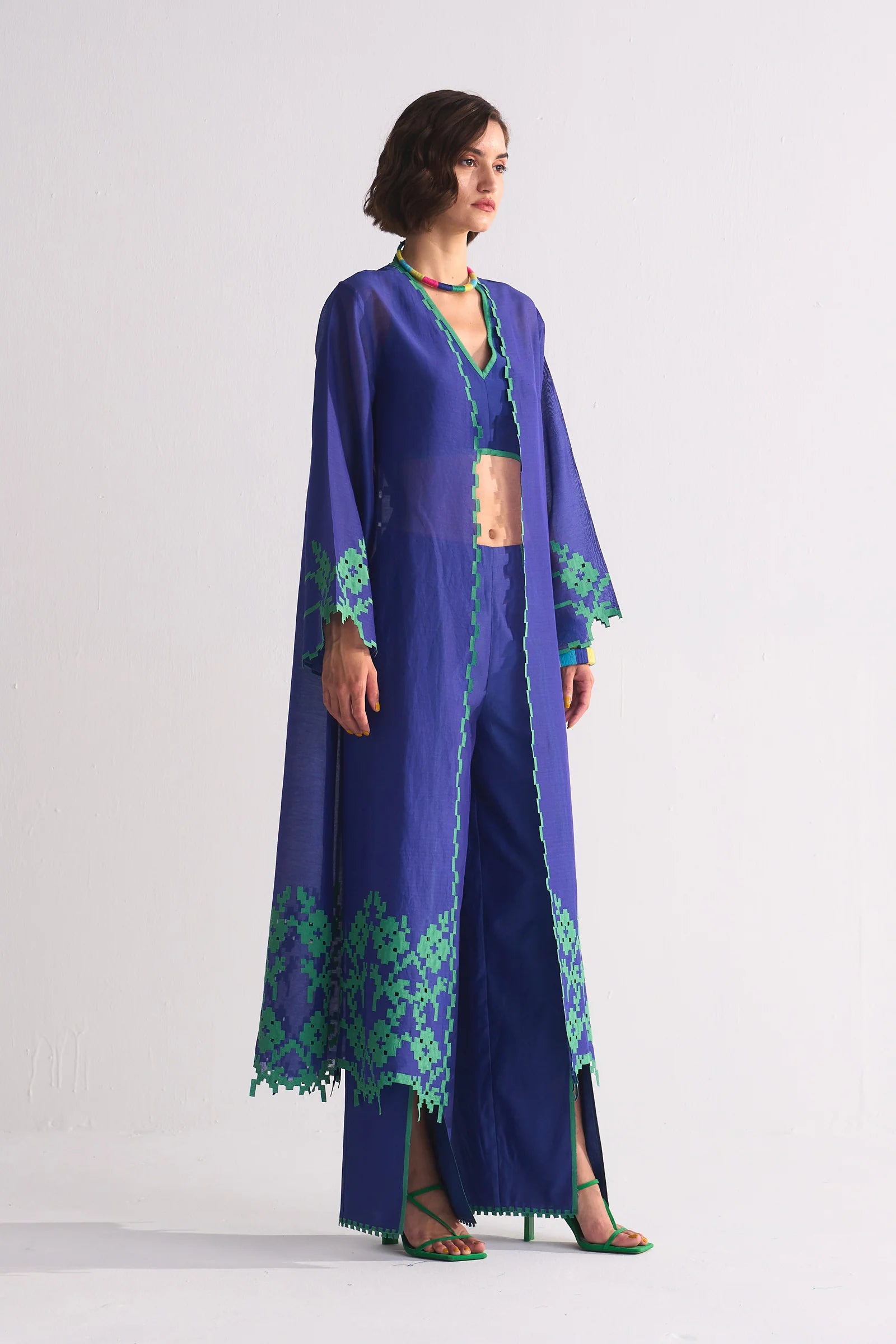 A long indigo Cotton Silk Chanderi jacket featuring a large green geometric floral appliqué on the back and matching cutwork along the hem and sleeves.