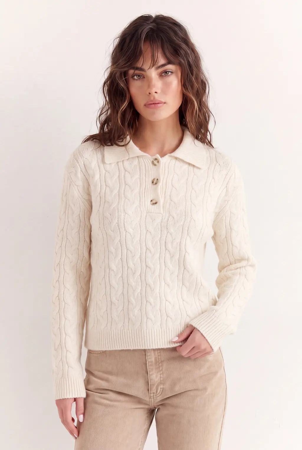 Close-up of luxury white cable knit cotton polo sweater showing vertical knit pattern and buttons