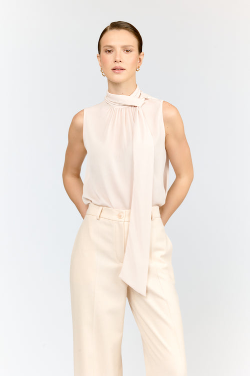 Woman wearing a sleeveless top and pants with a scarf on a white background