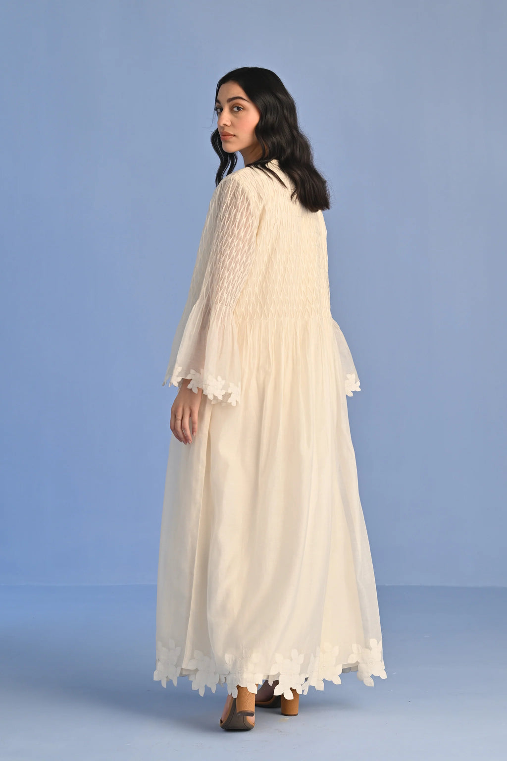 A floor-length ivory Cotton Silk Chanderi dress with a pleated skirt, featuring intricate geometric cutwork panels on the bodice and hemline.