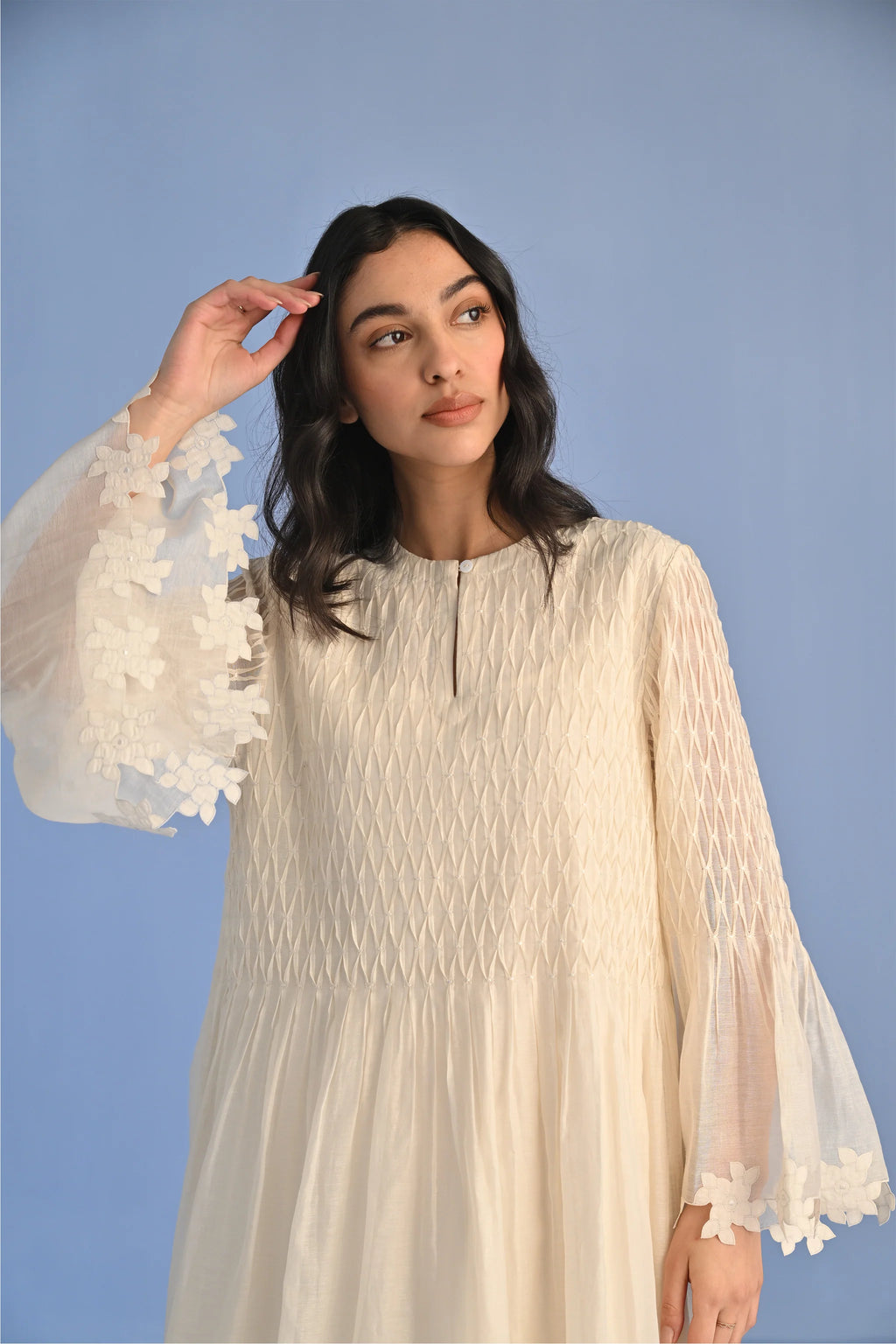 A floor-length ivory Cotton Silk Chanderi dress with a pleated skirt, featuring intricate geometric cutwork panels on the bodice and hemline.