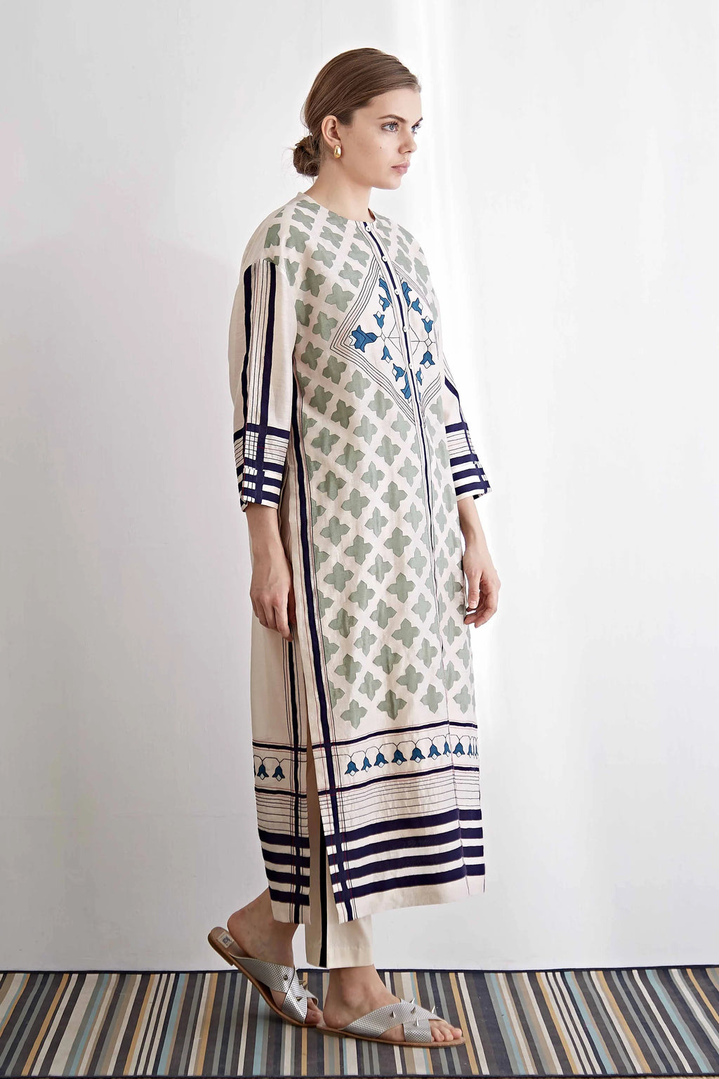 Woman wearing a long, patterned dress with vertical stripes on a white background