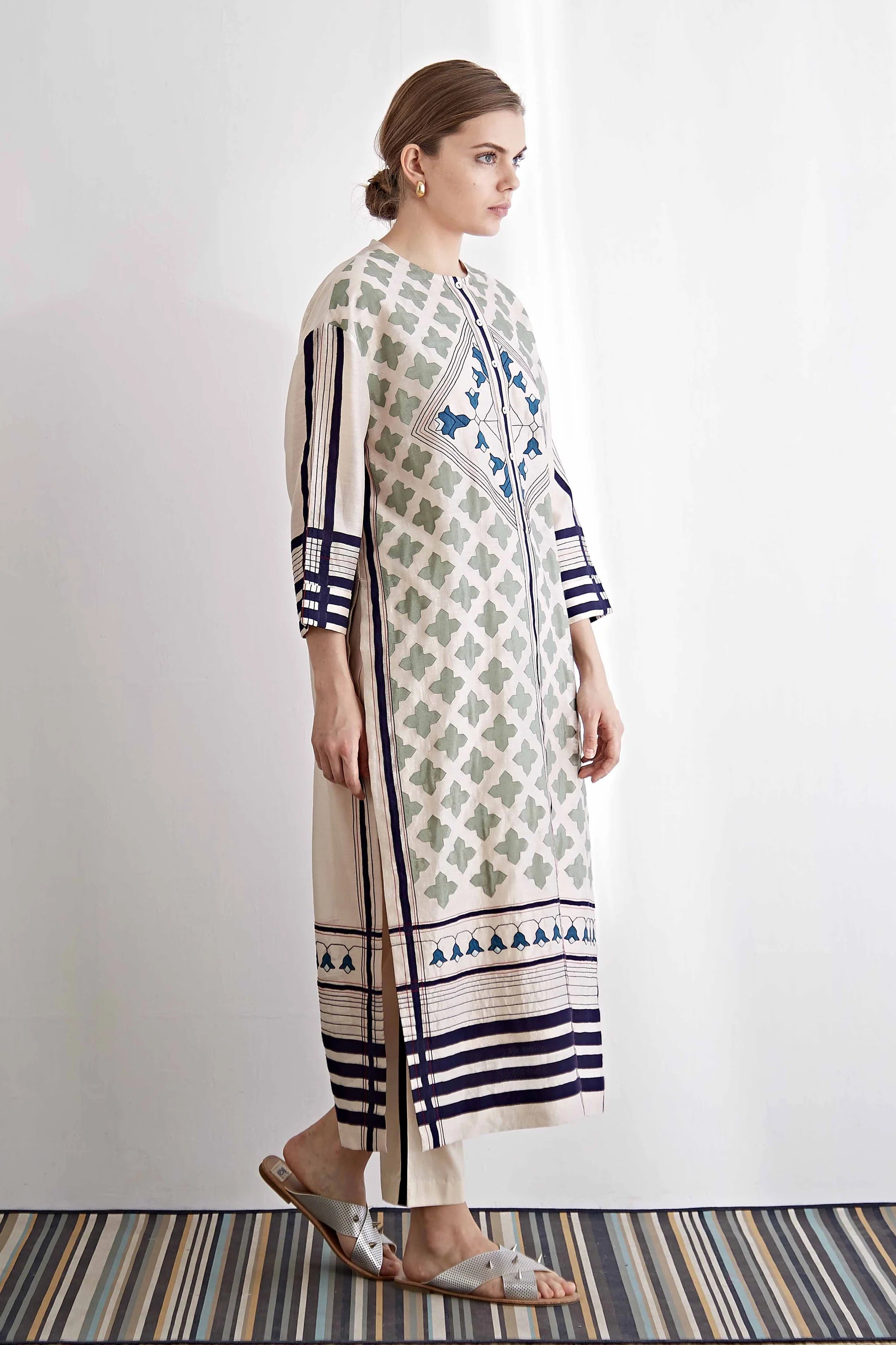 Woman wearing a long, patterned dress with vertical stripes on a white background