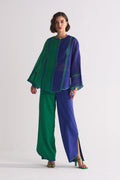 A model in a round-hem indigo Chanderi shirt with green colour-blocked panels and geometric hand-cut appliqué along the hem and shoulders.