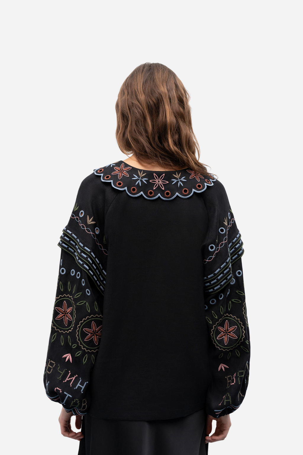 Black embroidered blouse worn by a person on a white background