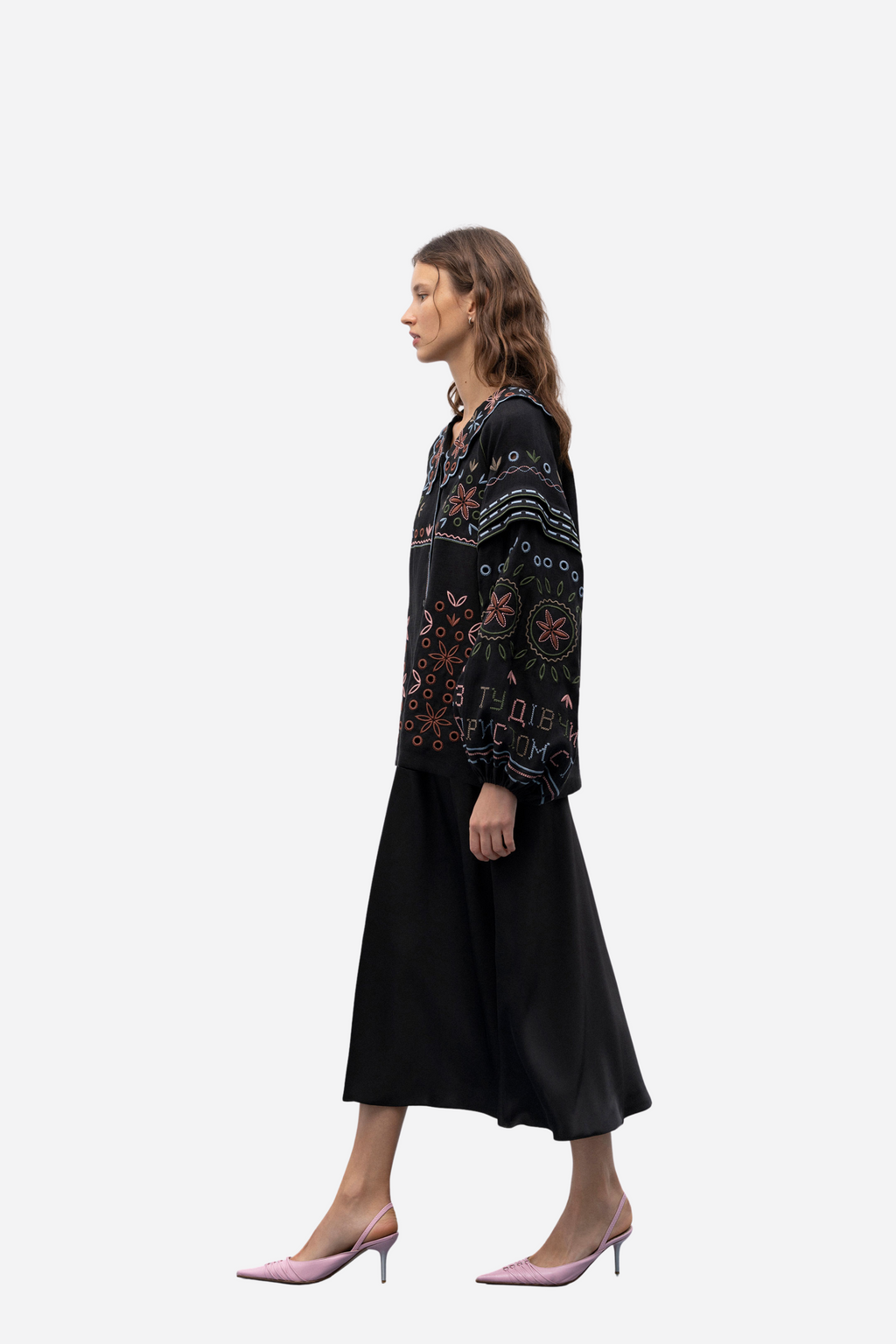 Woman wearing a black patterned blouse and black skirt on a white background