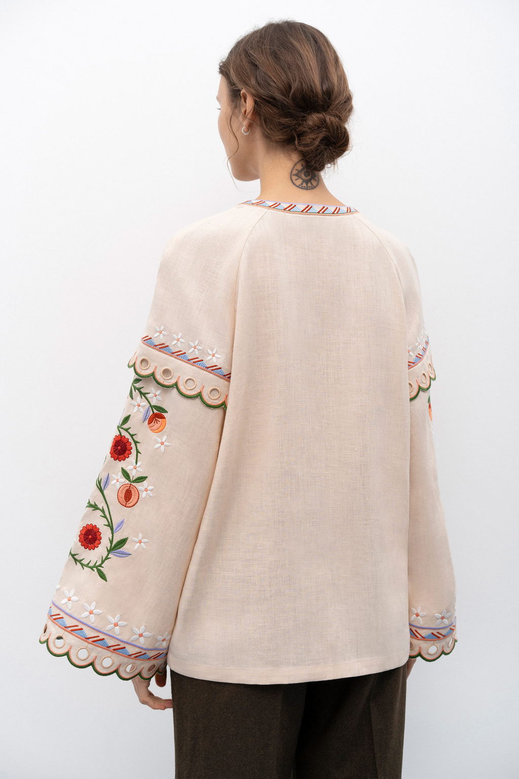 Beige embroidered blouse worn by a person on a white background