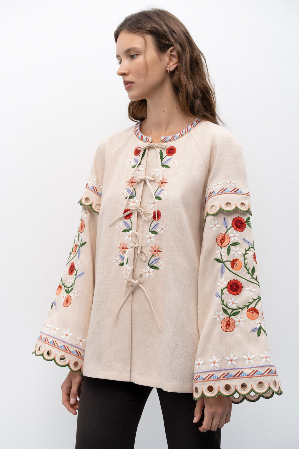 Woman wearing a beige blouse with black floral patterns on a white background