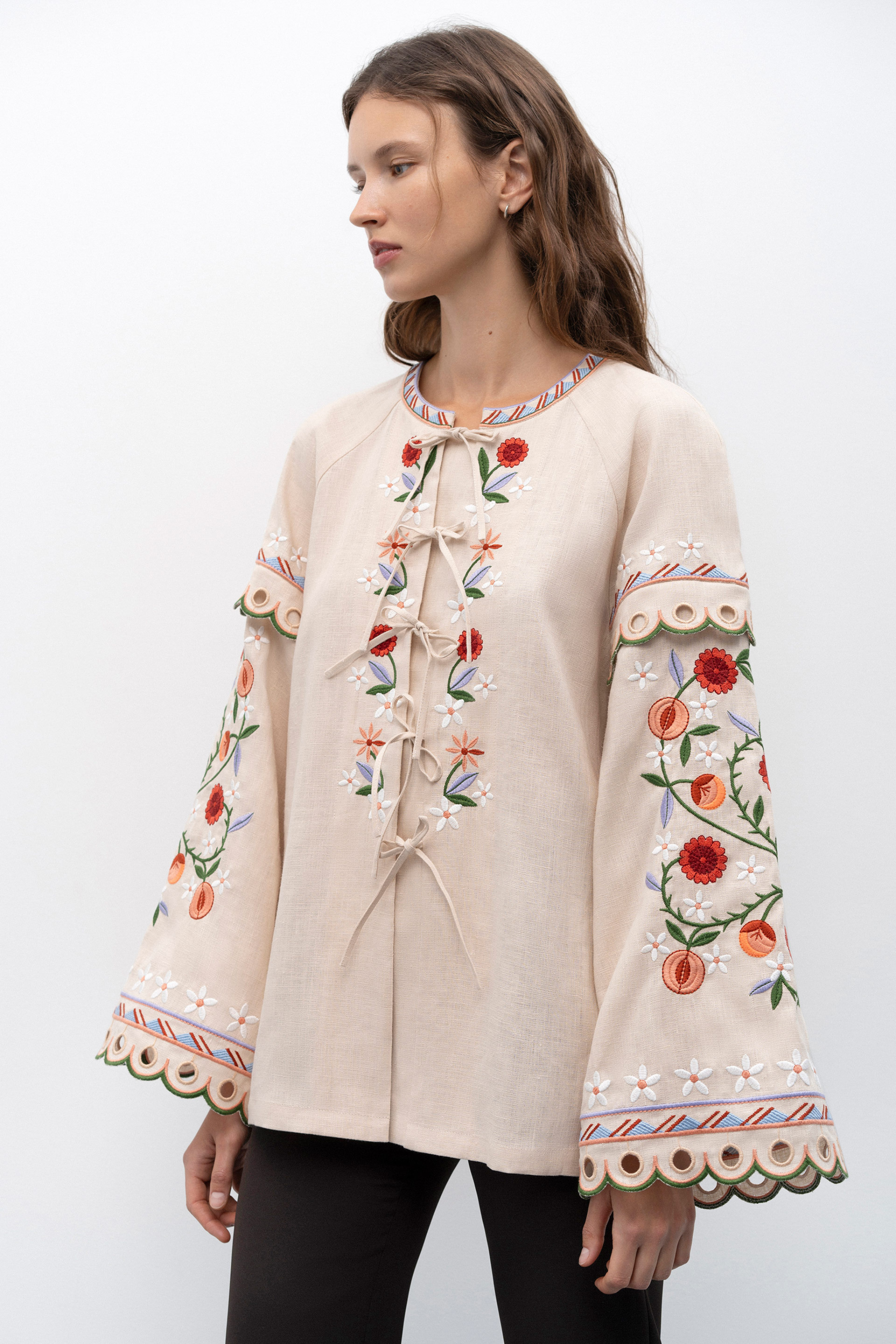 Woman wearing a beige blouse with black floral patterns on a white background