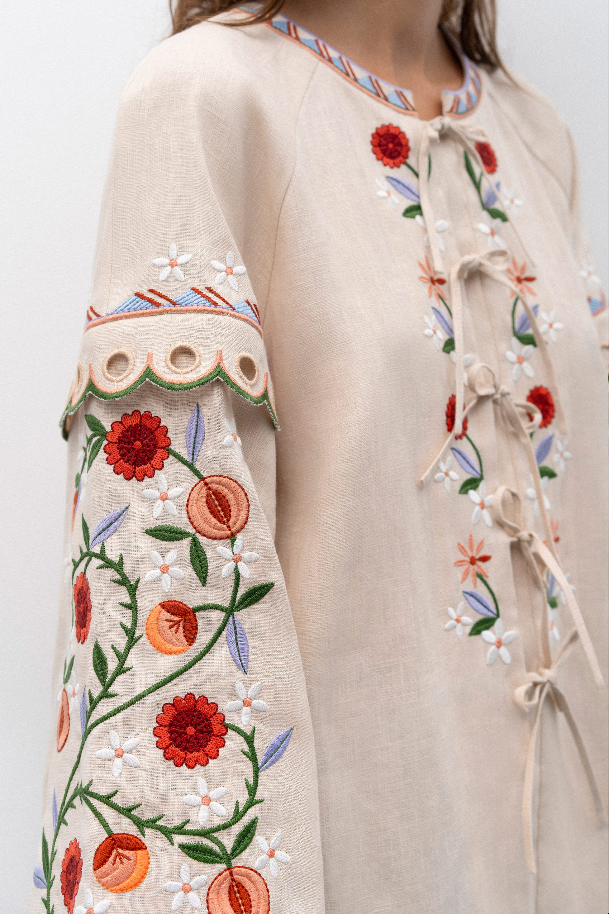 Woman wearing a patterned blouse and blue jeans against a white background