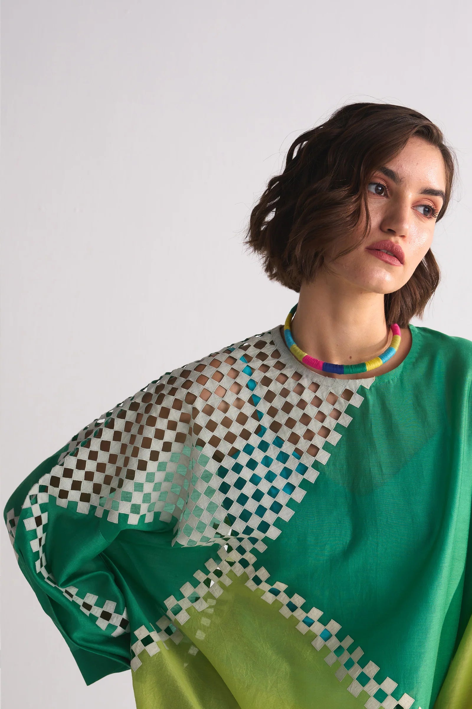 Woman wearing a green and patterned top against a white background