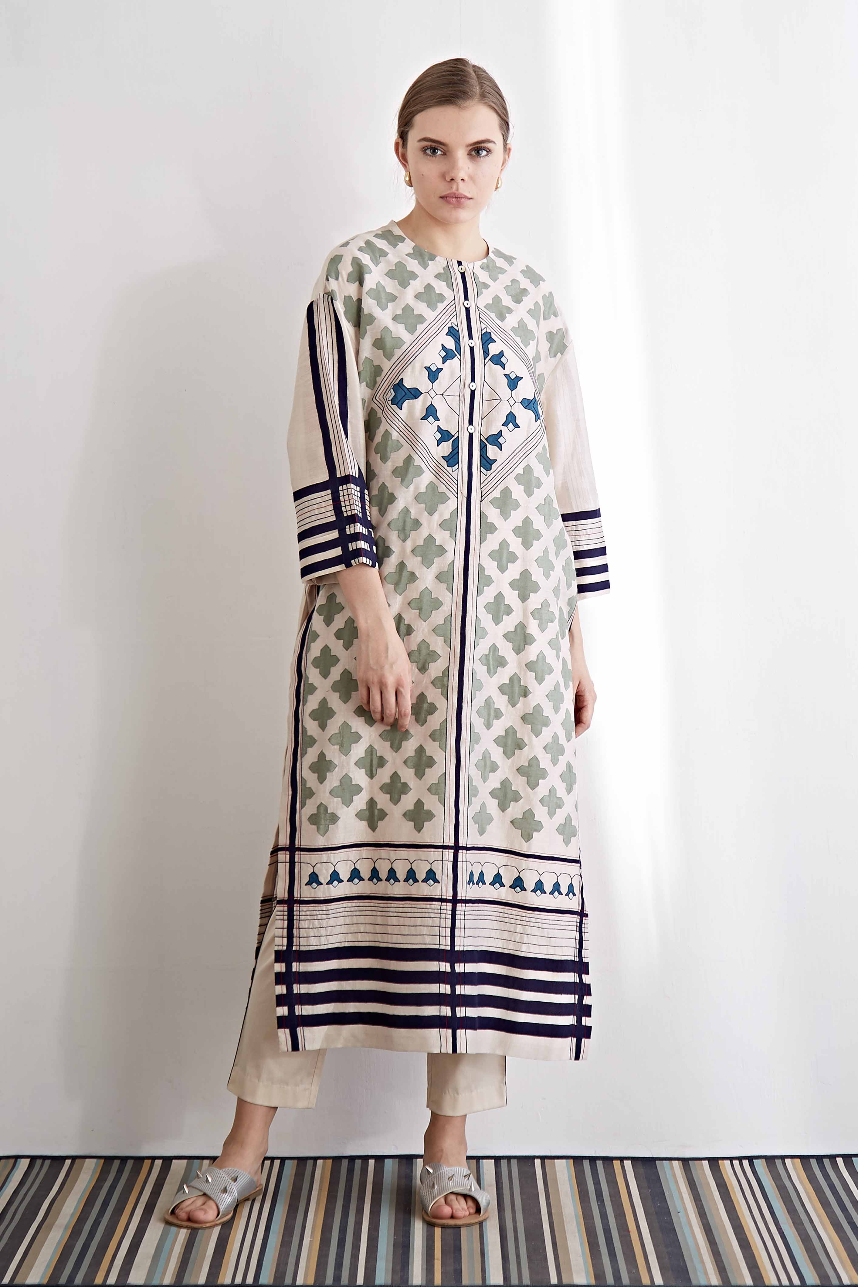 Woman wearing a long, patterned dress with a white background