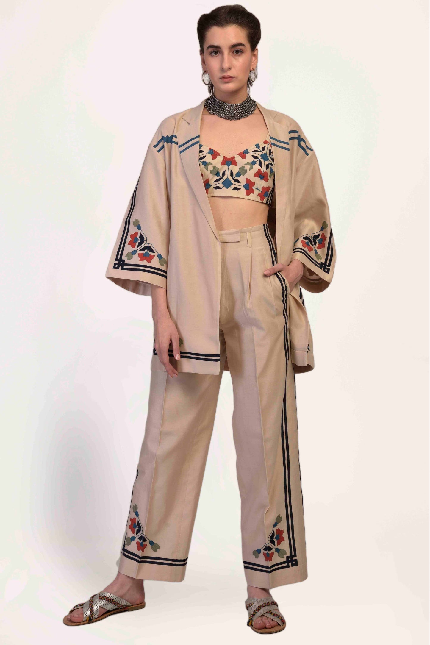 Woman wearing a beige outfit with floral embroidery on a white background