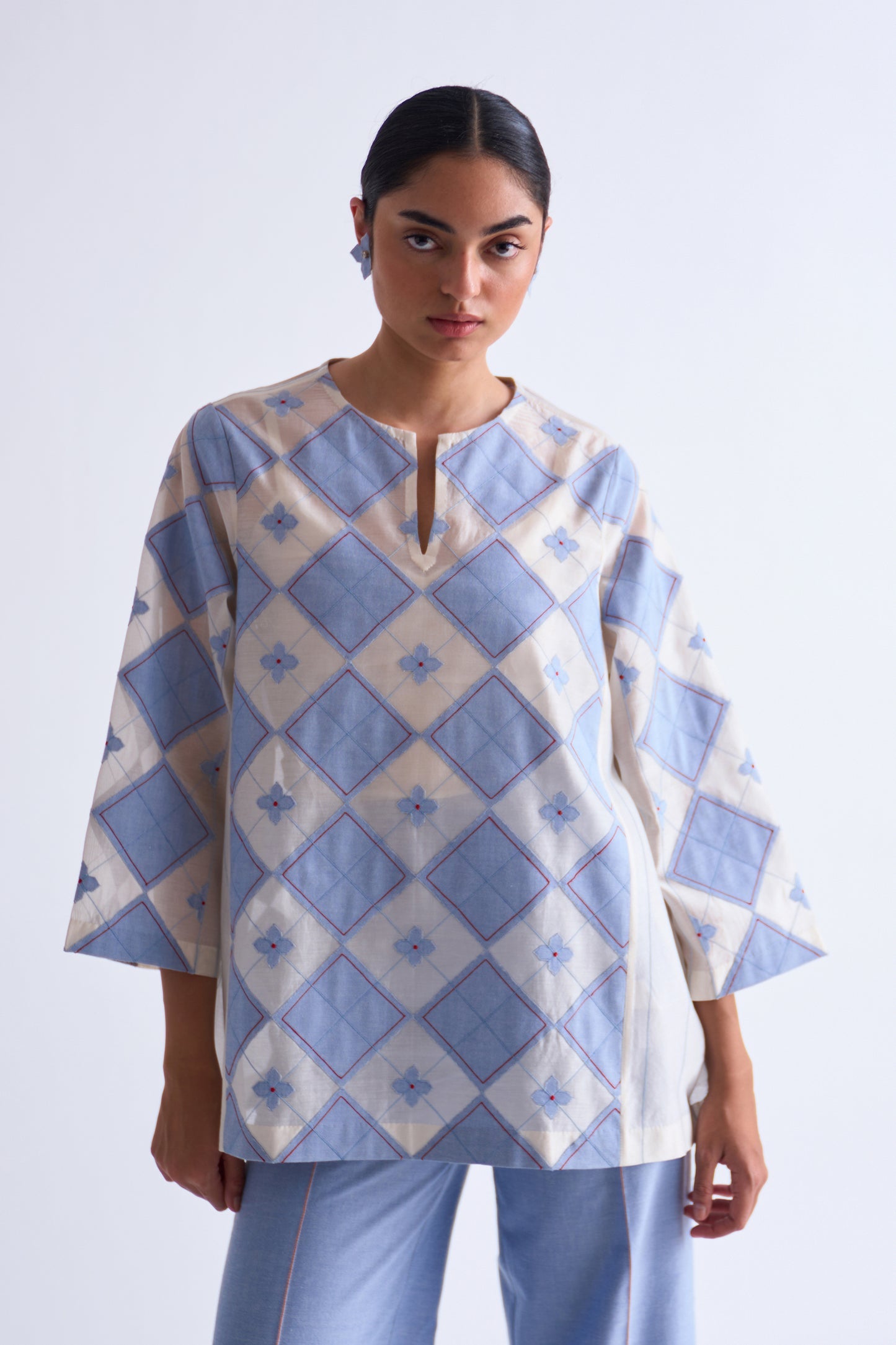 Woman wearing a blue and white patterned top on a white background