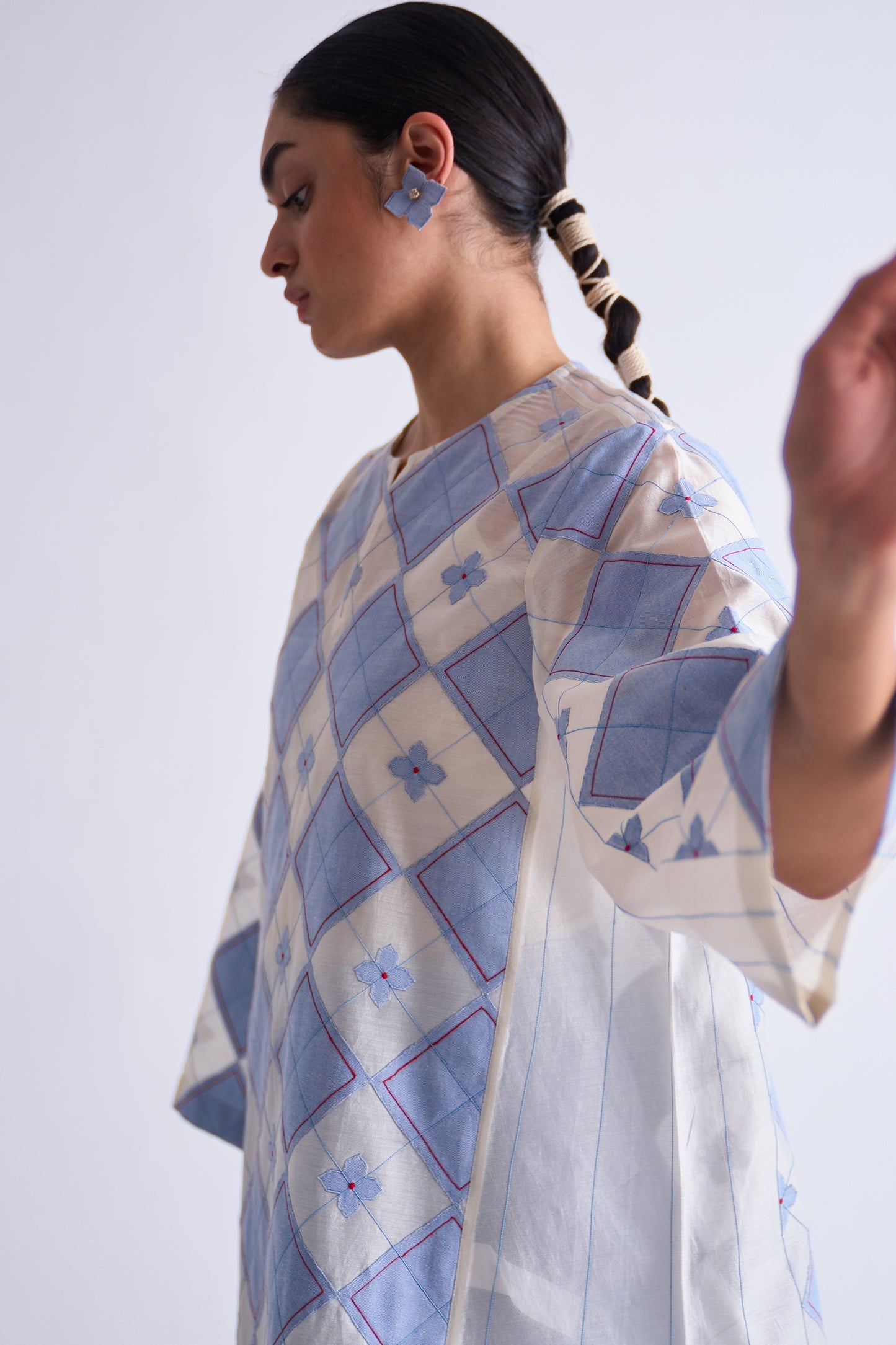 Woman wearing a blue and white patterned dress against a plain background