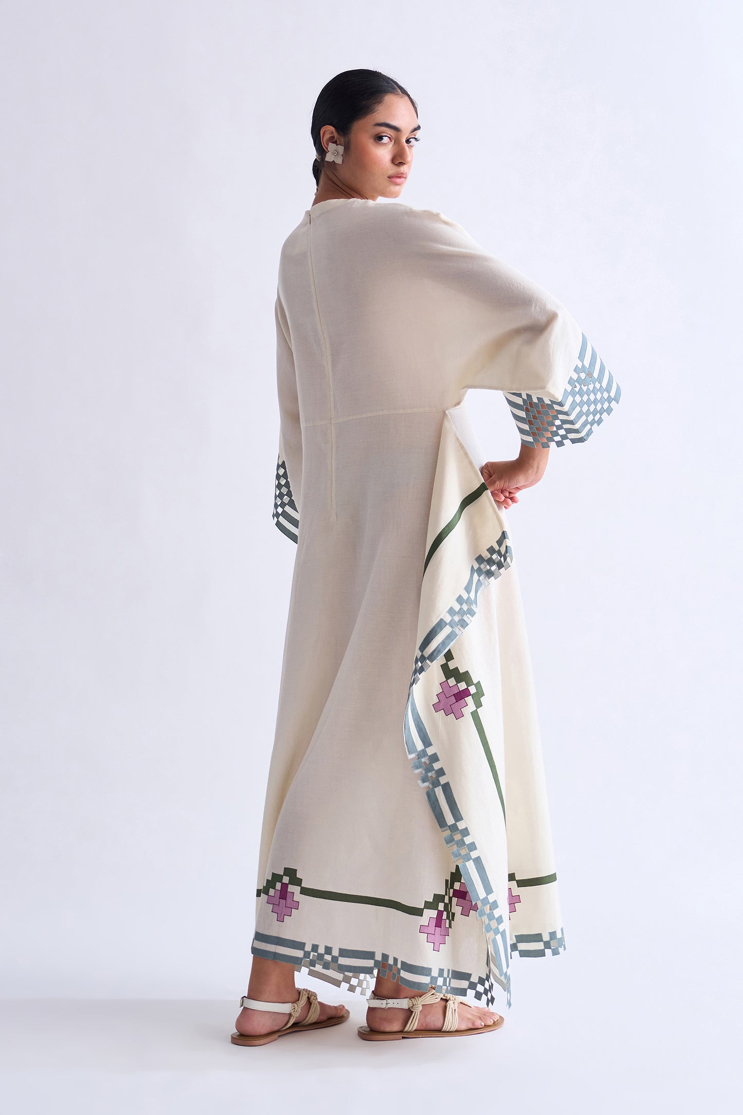 Woman wearing a beige dress with floral patterns on a white background